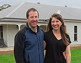 Brendan & Karen smiling in front of kit home